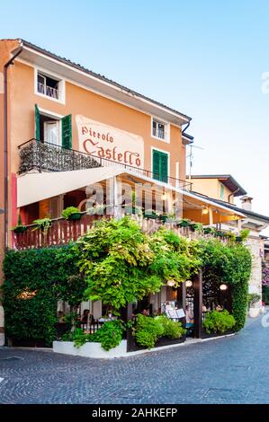 Sirmione, Lombardei, Italien - 12 September 2019: Gemütliches Restaurant mit grünen Trauben mit Terrasse im Zentrum von Sirmione Altstadt in L überwachsen Stockfoto