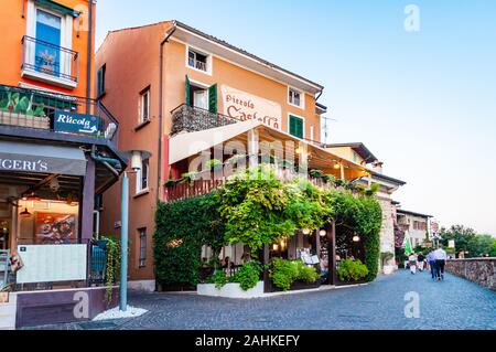 Sirmione, Lombardei, Italien - 12 September 2019: Gemütliches Restaurant mit grünen Trauben mit Terrasse im Zentrum von Sirmione Altstadt in L überwachsen Stockfoto