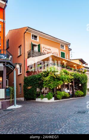 Sirmione, Lombardei, Italien - 12 September 2019: Gemütliches Restaurant mit grünen Trauben mit Terrasse im Zentrum von Sirmione Altstadt in L überwachsen Stockfoto