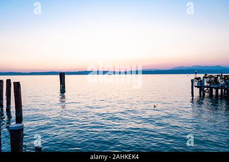 Sirmione, Lombardei, Italien - 12 September 2019: Sonnenuntergang über dem Gardasee mit gemütlichen Badestege schwimmende Schiffe und Süßwasser Vögel ruhen auf Wasser su Stockfoto