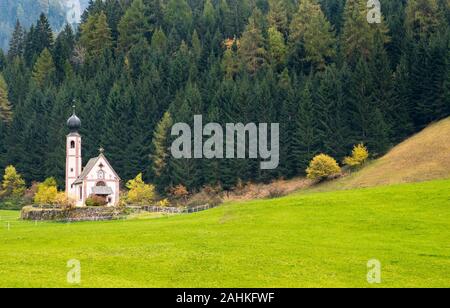 Die kleine und schöne Kirche des Heiligen Johannes, Ranui, chiesetta di San Giovanni in Ranui Runen Südtirol Italien, umgeben von grünen Wiesen, Wald ein Stockfoto