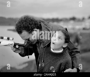 Mann, durch Teleskop als seine Tochter bis in den Himmel im Awe aussieht. Stockfoto