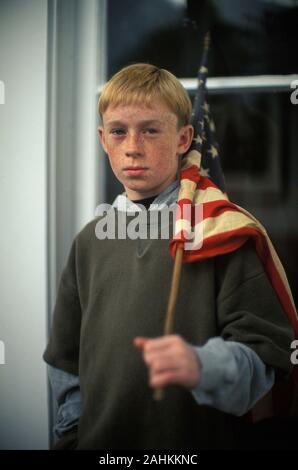 Ein Junge steht mit einer amerikanischen Flagge auf seiner Schulter. Stockfoto