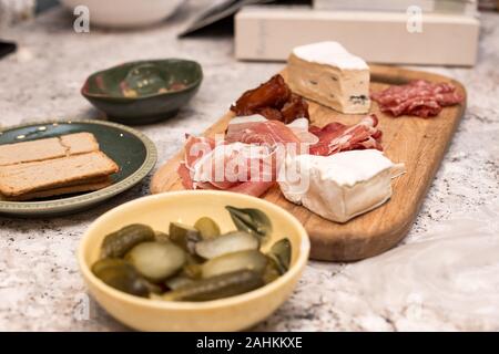 Ein Fleisch-und Käse-Wurstbrett mit Cracker und Gurken auf der Seite. Stockfoto