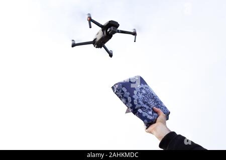 Eine autonome Postzustelldrohne mit einer Hand, die ein Paket in den Himmel hält. Stockfoto