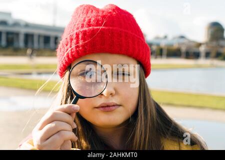 Schöne blonde Mädchen im Teenageralter in einem roten Strickmütze durch Suchen Stockfoto