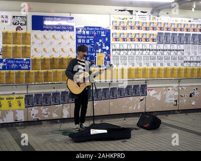 Blick auf ein Straßenmusiker spielen vor einer Wand aus Protest Poster in einer U-Bahn in Hong Kong abgedeckt Stockfoto