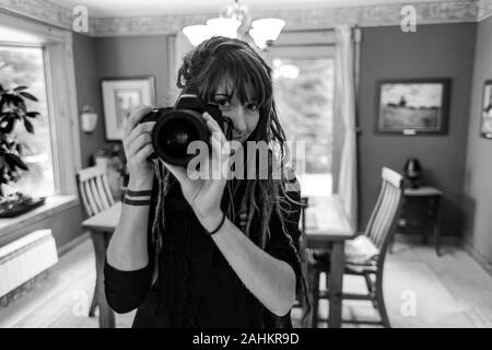 Schwarze und weiße Nahaufnahme Portrait von professionellen Fotografen hand-Holding eine DSLR-Kamera. Natürlich schönes Mädchen mit Dreadlocks und Tätowierungen. Stockfoto