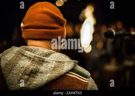 Rückseite Nahaufnahme von junge musicaldarsteller Singen auf das Mikrofon an geselliges Beisammensein in der Nähe der Feuer. Selektiver Fokus mit unscharfem Hintergrund. Stockfoto