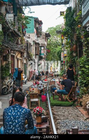 Touristen genießen Café im Freien Sitzplätze auf der Tracks in Hanoi die unbeliebten Zug Straße, Ngo 224 Le Duan, in der Altstadt. Stockfoto