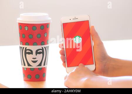 Calgary, Alberta. Kanada 28.Dezember 2019. Eine Person, die ein mit dem iPhone App mit einem Starbucks Kaffee während Weihnachten. Starbucks guy" verbrachte 22 Jahre Stockfoto