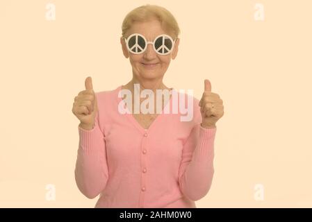 Gerne ältere Frau lächelnd, während eine Sonnenbrille mit peace Zeichen und geben Daumen bis Stockfoto