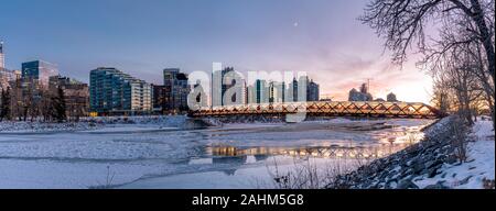 Blick auf die Skyline von Calgary an einem kalten Wintertag. Bow River und der Peace Bridge sind sichtbar im Bild. Bürotürme in den Kern der Innenstadt sind auch. Stockfoto