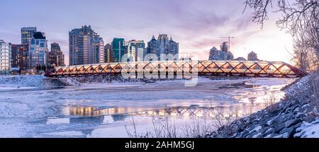 Blick auf die Skyline von Calgary an einem kalten Wintertag. Bow River und der Peace Bridge sind sichtbar im Bild. Bürotürme in den Kern der Innenstadt sind auch. Stockfoto