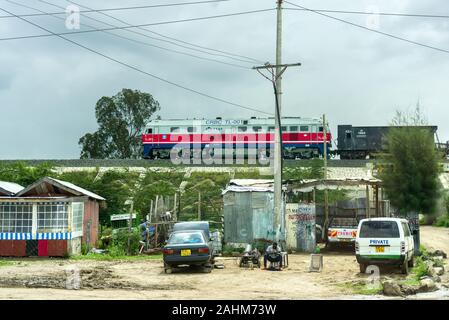 Ein DF8B Diesel lok Güterzug vorbei an Hütten auf der SGR-standard Gauge Railway, Kenia Stockfoto