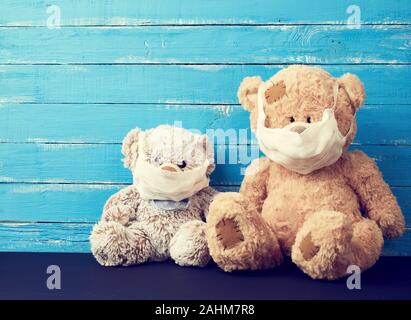 Zwei Bären sitzen in weißen medizinische Masken auf einem blauen Hintergrund aus Holz. Lungen- und Bronchialheilkunde. Stockfoto