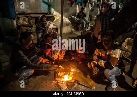 Kolkata. 30 Dez, 2019. Die Menschen drängen sich in ein Feuer durch einen kalten Winterabend in Kolkata, Indien am Dez. 30, 2019. Das India Meteorological Department (IMD) am Sonntag eine rot-codierten Warnung für Teile des Landes als eine kalte Welle zu fegen über das Land weiter. Beamte sagten eine Atempause von der Kälte von Dez. 31 bis Jan. 2 erwartet wurde. Credit: tumpa Mondal/Xinhua/Alamy leben Nachrichten Stockfoto