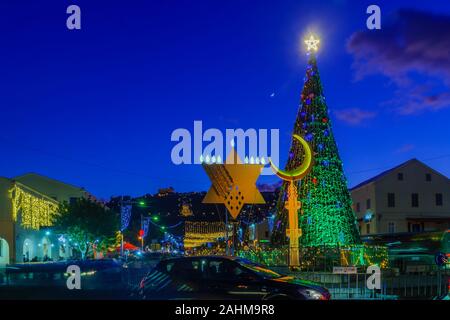 Haifa, Israel - 29. Dezember 2019: Der Urlaub von Urlaub in der deutschen Kolonie, mit einem Weihnachtsbaum, Hanukkah Menorah, muslimische Halbmond und der Baha Stockfoto