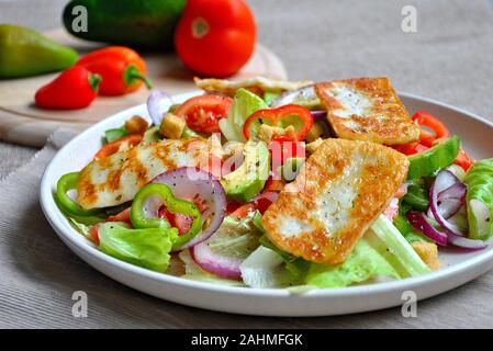 Mittlerer Osten gegrillter Halloumi-Käsesalat mit Avocado, Orangen, Kirschtomaten, roten Zwiebeln, Rucola-Rübenblättern. . Stockfoto