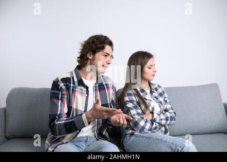 Junge Mann beleidigt Freundin beim Sitzen auf einem Sofa. Stockfoto