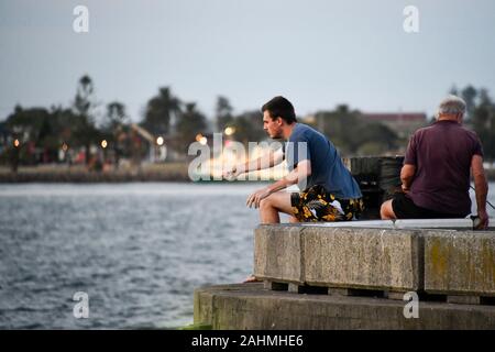 Männer aus Fishing Pier auf Sommer Abend in Newcastle Hafen Stockfoto