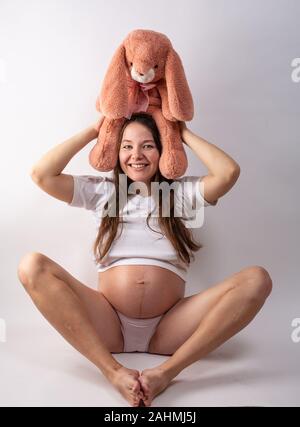 Close-up schwangeren Bauch mit Hase Spielzeug. Schöne schwangere Frau. Schwangerschaft, Elternschaft, Vorbereitung und Erwartung Konzept. Stockfoto