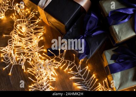 Goldene Licht von Garland Glühbirnen. Weihnachtliche Atmosphäre im Haus. Das neue Jahr Dekor und Geschenkboxen. Stockfoto
