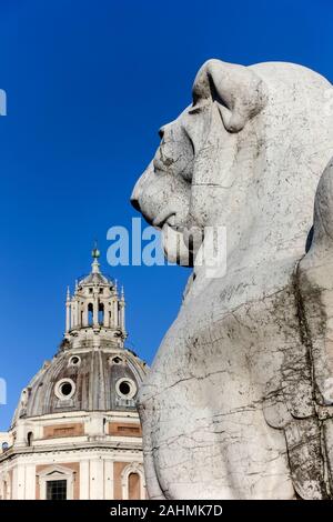 Geflügelte Löwe Statue, Denkmal für Victor Emmanuel II.. Altar des Vaterlandes. Im Hintergrund Kuppel der Kirche Heilige Maria von Loreto. Rom, EU. Nahaufnahme Stockfoto