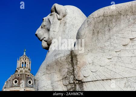 Geflügelte Löwe Skulptur, Denkmal Victor Emmanuel II. Altar des Vaterlandes. Im Hintergrund Kuppel der Kirche Heilige Maria von Loreto. Rom. Nahaufnahme Stockfoto