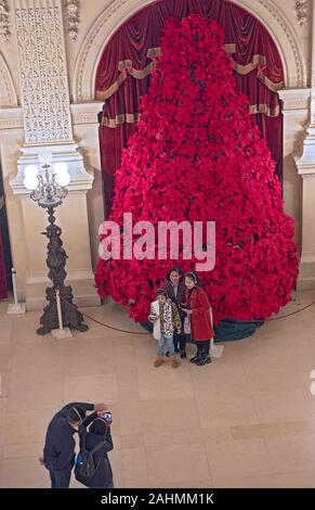 Touristen nehmen Handy Fotos vor einem riesigen Weihnachtsbaum in der Aula der Leistungsschalter Herrenhaus in Newport, Rhode Island. Stockfoto