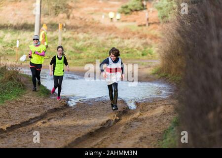 Sutton, Suffolk, VEREINIGTES KÖNIGREICH 15. Dezember 2019: A-Junioren unter 18 cross country running Rennen durch einen schlammigen Landschaft Kurs Stockfoto