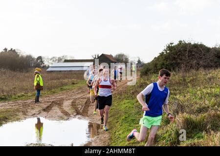 Sutton, Suffolk, VEREINIGTES KÖNIGREICH 15. Dezember 2019: eine Erwachsene über 18 cross country running Rennen durch einen schlammigen Landschaft Kurs Stockfoto