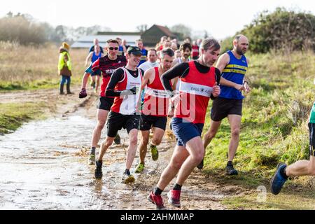 Sutton, Suffolk, VEREINIGTES KÖNIGREICH 15. Dezember 2019: eine Erwachsene über 18 cross country running Rennen durch einen schlammigen Landschaft Kurs Stockfoto