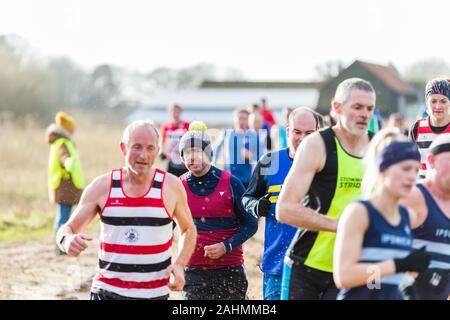 Sutton, Suffolk, VEREINIGTES KÖNIGREICH 15. Dezember 2019: eine Erwachsene über 18 cross country running Rennen durch einen schlammigen Landschaft Kurs Stockfoto