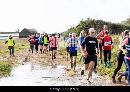 Sutton, Suffolk, VEREINIGTES KÖNIGREICH 15. Dezember 2019: eine Erwachsene über 18 cross country running Rennen durch einen schlammigen Landschaft Kurs Stockfoto