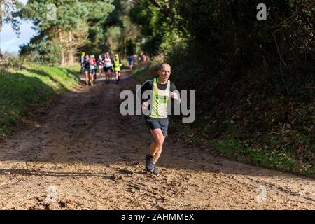 Sutton, Suffolk, VEREINIGTES KÖNIGREICH 15. Dezember 2019: eine Erwachsene über 18 cross country running Rennen durch einen schlammigen Landschaft Kurs Stockfoto