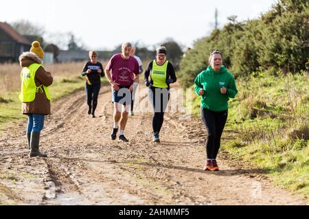 Sutton, Suffolk, VEREINIGTES KÖNIGREICH 15. Dezember 2019: eine Erwachsene über 18 cross country running Rennen durch einen schlammigen Landschaft Kurs Stockfoto