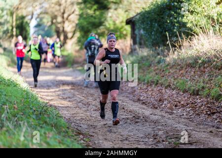 Sutton, Suffolk, VEREINIGTES KÖNIGREICH 15. Dezember 2019: eine Erwachsene über 18 cross country running Rennen durch einen schlammigen Landschaft Kurs Stockfoto