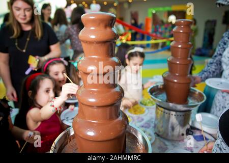 Brunnen Schokolade mit Früchten. Kindergeburtstag. Hausgemachte Schokolade Brunnen Fondue mit Marshmallow auf einem Spieß tropft in Schokoladensauce Stockfoto