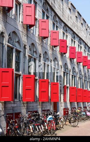 Fassade der mittelalterlichen Huis (Haus) Zoudenbalch mit ausgeprägten hellen roten Luken en zahlreiche Fahrräder davor geparkt. Utrecht, Niederlande. Stockfoto