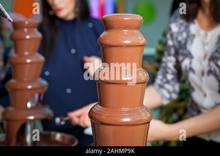 Brunnen Schokolade mit Früchten. Kindergeburtstag. Hausgemachte Schokolade Brunnen Fondue mit Marshmallow auf einem Spieß tropft in Schokoladensauce Stockfoto