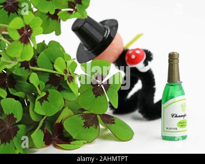 Schornsteinfeger kotzt hinter cloverleafs vor eine Flasche Champagner, Konzept der Kater nach Silvester Stockfoto