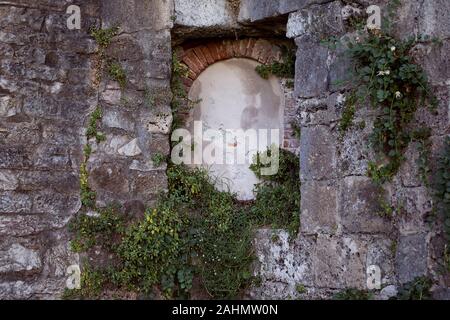 Bewachsenen Stein Steinwand mit leeren Rahmen. Romantische geheimnisvollen Garten Hintergrund. Pflanzen an der Wand. Kopieren Sie Platz. Stockfoto