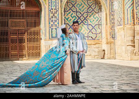 Hochzeit paar in traditioneller Kleidung vor der berühmten Registan Platz, Samarkand, Usbekistan, in Zentralasien posing Stockfoto
