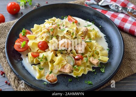 Österreichische Mahlzeit mit typischen Pasta und geräucherter Lachs mit Sahnesoße, serviert auf einer schwarzen Platte Stockfoto