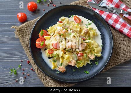 Österreichische Mahlzeit mit typischen Pasta und geräucherter Lachs mit Sahnesoße, serviert auf einer schwarzen Platte Stockfoto