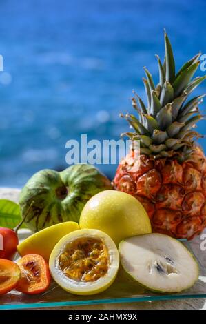 Tropische Früchte Sammlung, Custard Apple oder Grün reif cherymoia, Maracuja, Ananas, Mango, tamarillo Exotische Früchte auf blaues Meer Hintergrund in Stockfoto