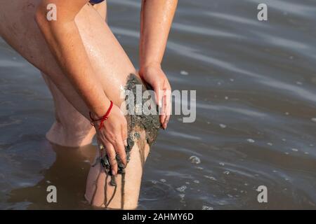 Frau Anwendung auf ihrem Körper Knie salzig Heilschlamm in See Stockfoto