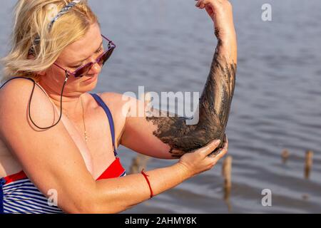 Frau Anwendung auf ihrem Körper salzig Heilschlamm an der Winkelverschraubung im See Stockfoto