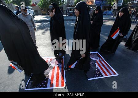 Bagdad, Irak. 31 Dez, 2019. Irakische Demonstranten gehen auf uns nationale Flaggen während einer Demonstration gegen tödliche US-Luftangriffe auf Websites von einem schiitischen Miliz. Irakische trauernde am Dienstag stürmten das Gebäude der US-Botschaft in Bagdad die stark befestigte Grüne Zone. Credit: Ameer Al Mohmmedaw/dpa/Alamy leben Nachrichten Stockfoto